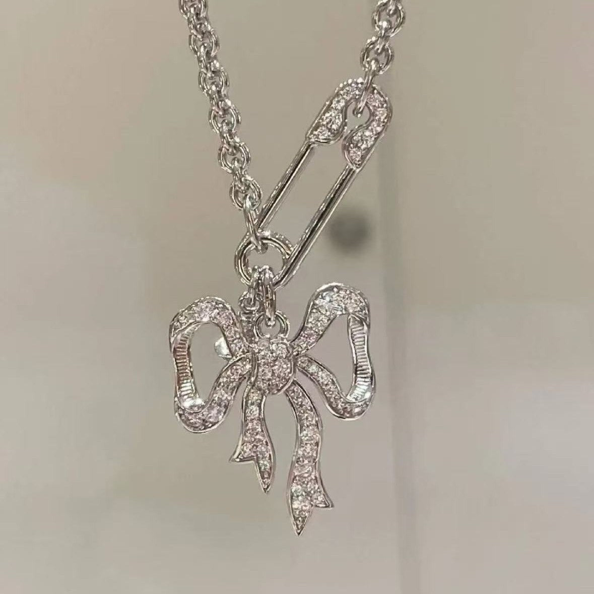 Silver bow pendant charm on chain necklace with sparkling clasp detail