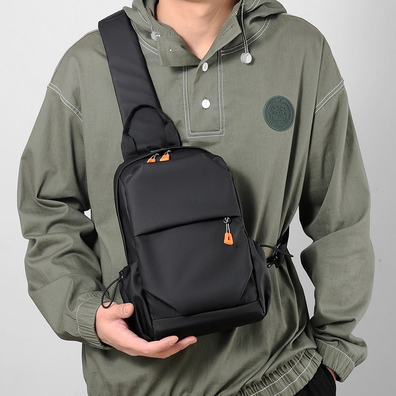 Black crossbody sling backpack bag with orange zipper pulls and adjustable shoulder strap