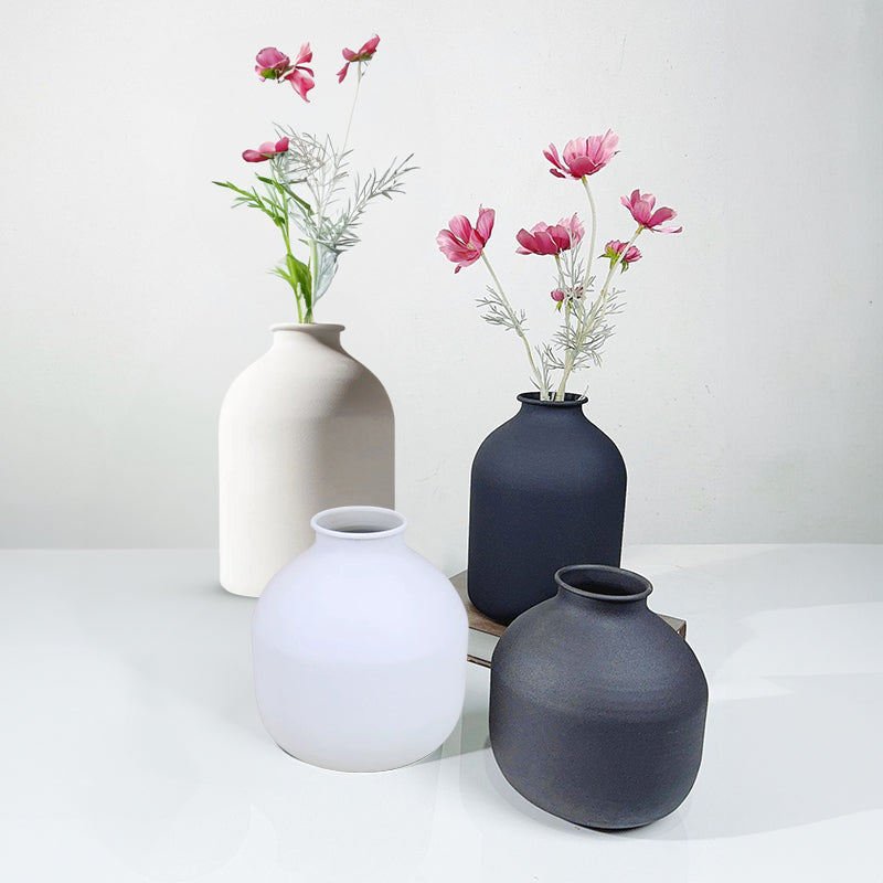 Matte black metal vase with rounded body, holding yellow and pink dried flowers