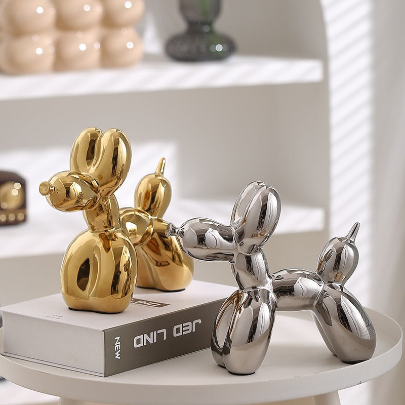 Gold and silver balloon dog figurines on a round display base