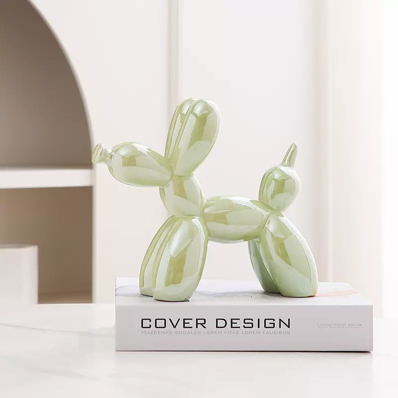 Light green balloon dog figurine with glossy reflective finish on a pedestal