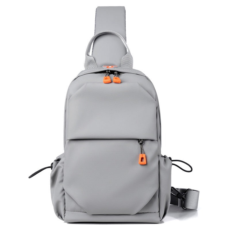 Gray crossbody sling backpack bag front view with orange zipper pulls and top handle