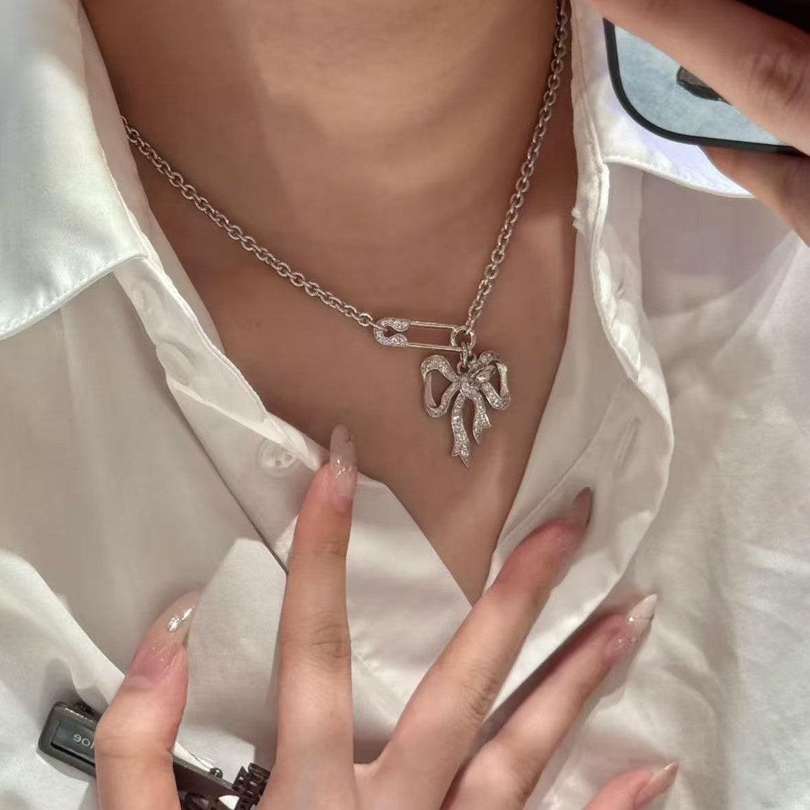 Silver chain necklace with bow pendant at the neckline