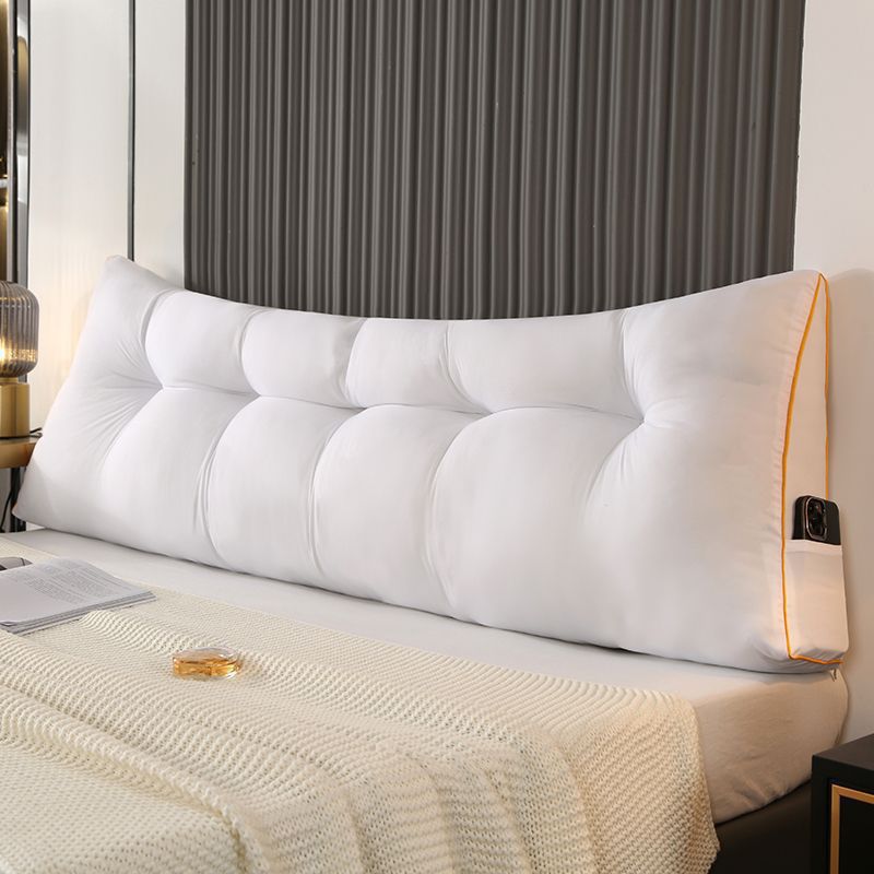 White triangular tufted bed backrest cushion with orange piping and side pocket.