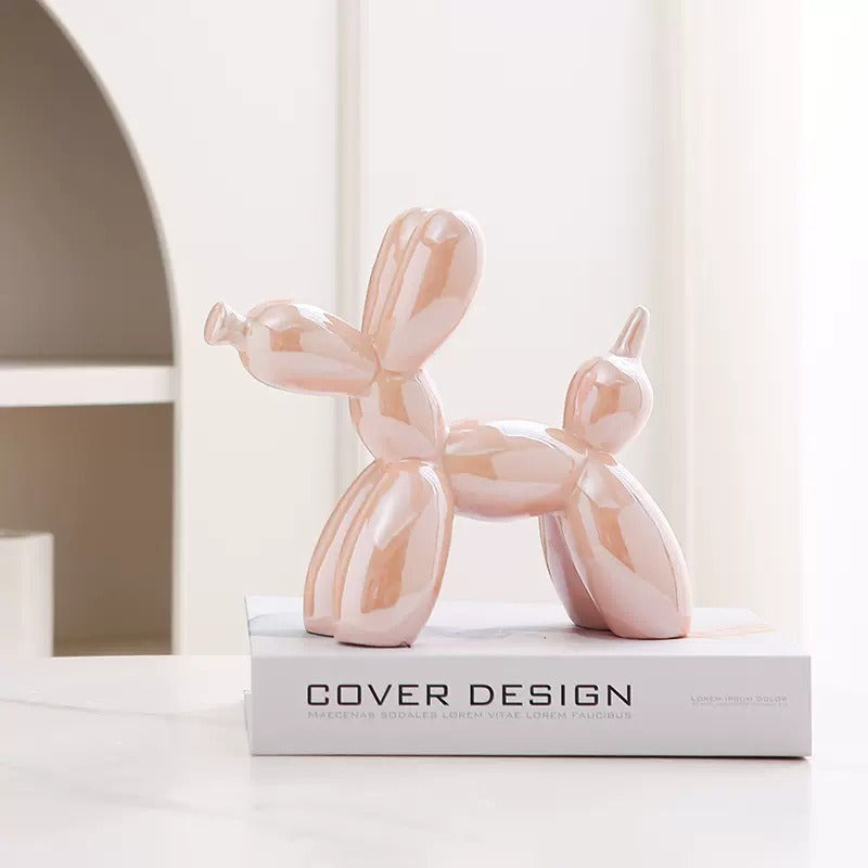 Blush pink balloon dog figurine with glossy reflective finish on a pedestal