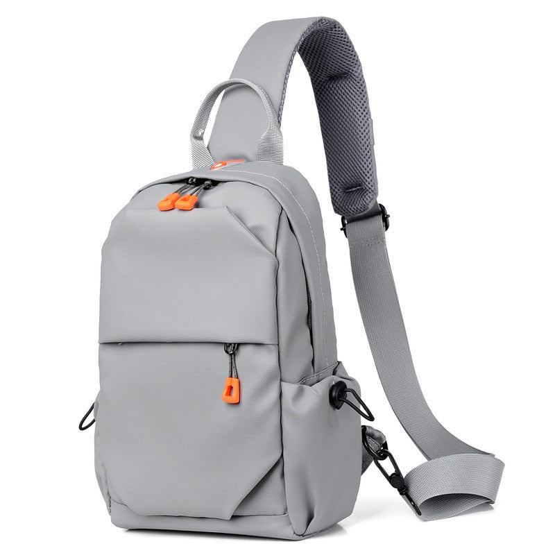 Gray crossbody sling backpack bag with orange zipper pulls and adjustable shoulder strap