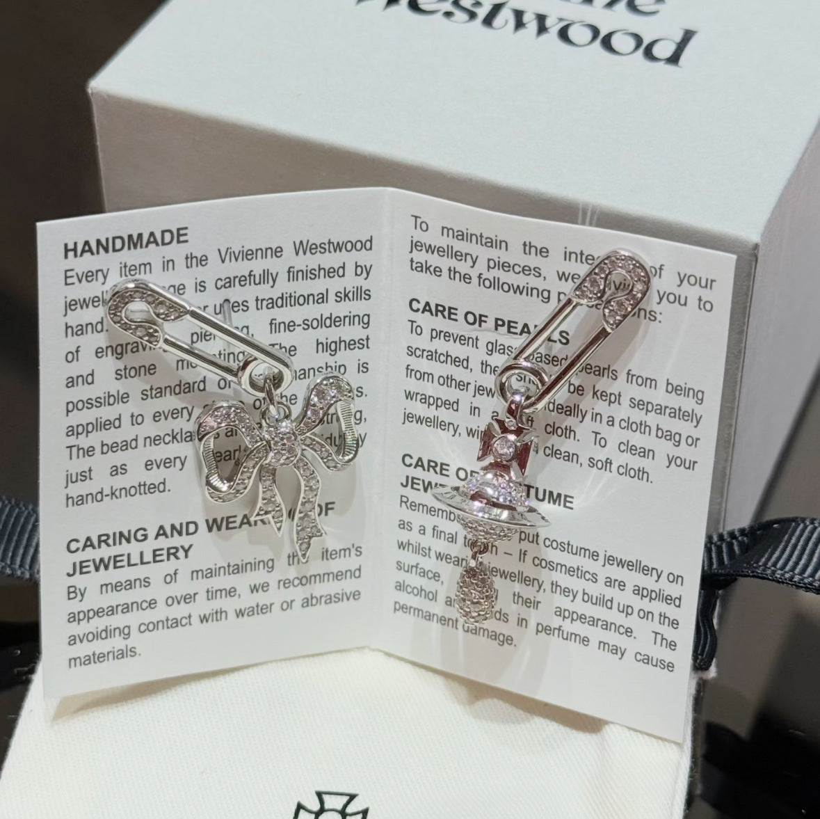 Silver bow pendant necklace on display box with care instructions card